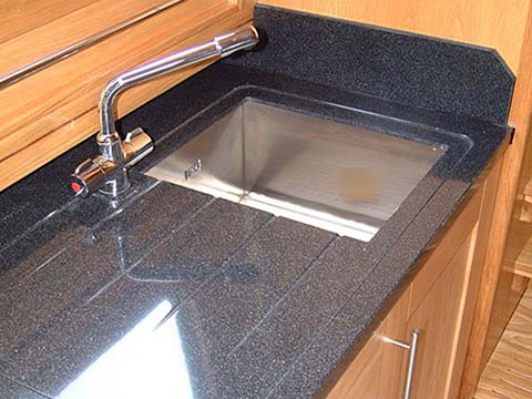 View shows solid surface material in galley with under mount sink and machined draining grooves 