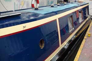 Narrowboat in workshop having final coats of pint applied