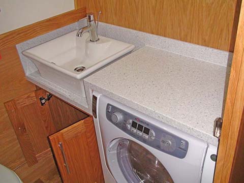 View of washing machine with corian worksurface over and vanity unit on residential narrowboat